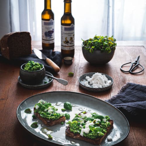 Leindotteröl und Leinöl mit Erbsenpüree, gerösteten Brot, veganem Feta und Basilikum