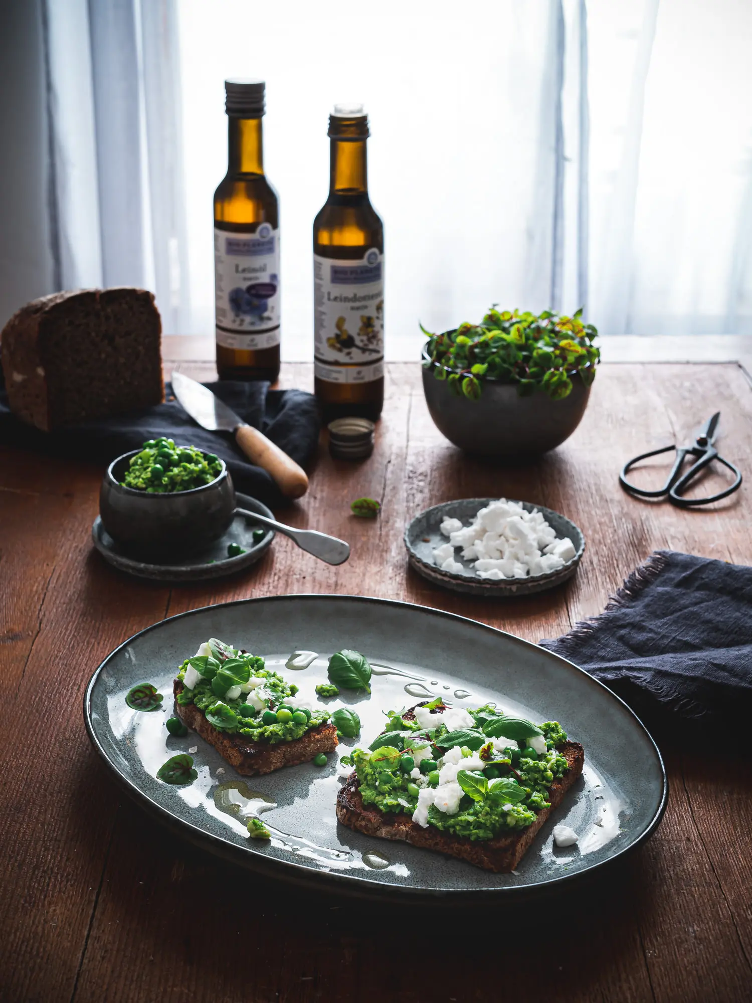 Leindotteröl und Leinöl mit Erbsenpüree, gerösteten Brot, veganem Feta und Basilikum