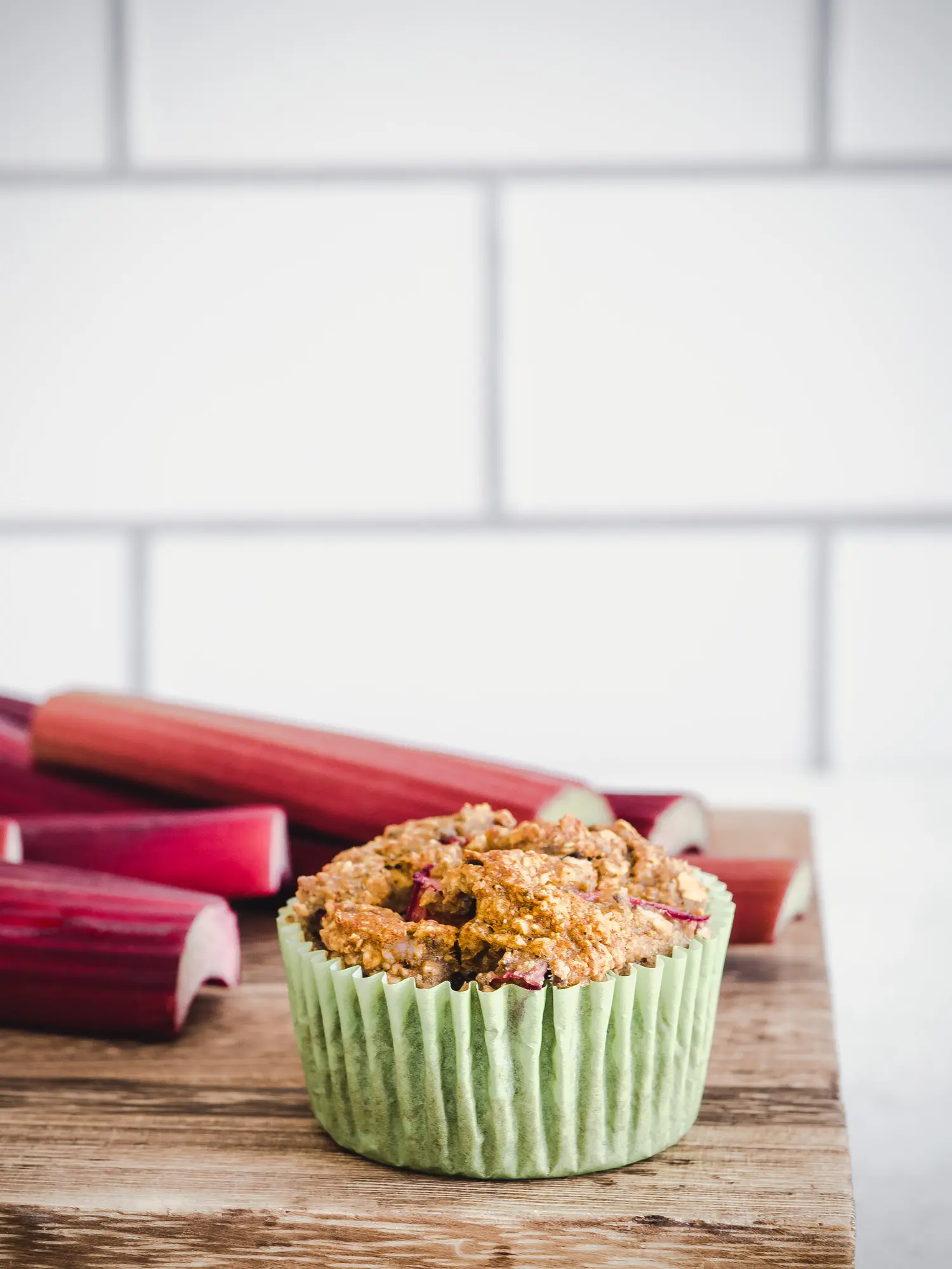 Joghurt Muffin mit Rhabarber im Close Up mit Rhabarber im Hintergrund