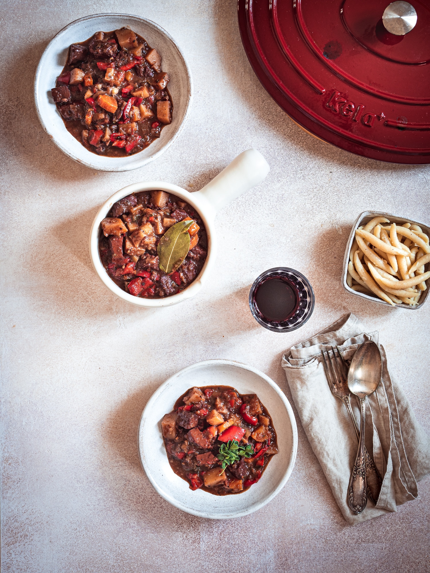 Veganes Gulasch auf zwei Tellern mit kela Bräter